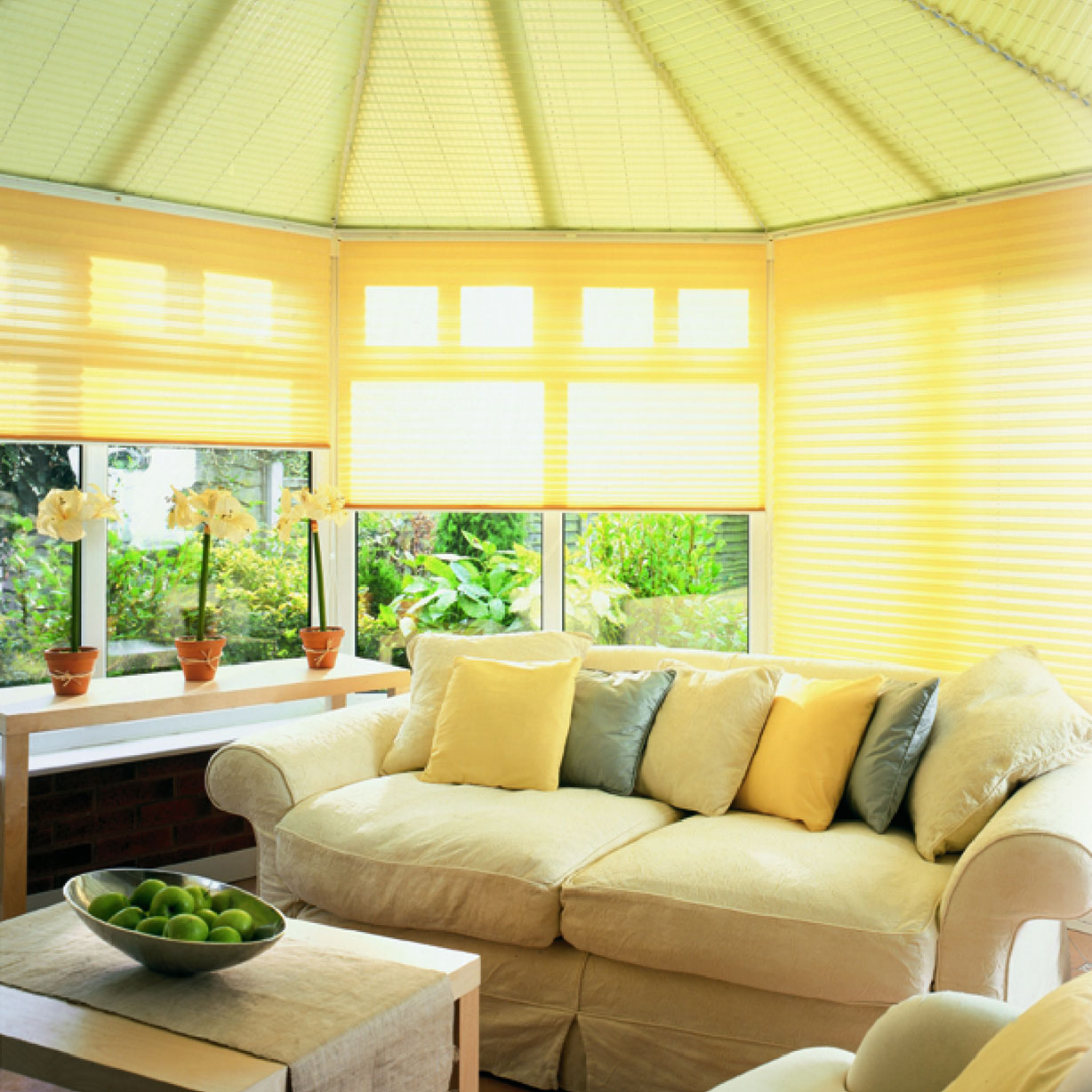 Yellow conservatory blinds in a conservatory with a cream sofa and yellow cushions
