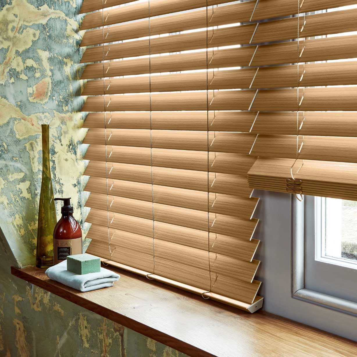 Close up of brown wood effect fauxwood venetian blind in a bathroom with wooden windowsill