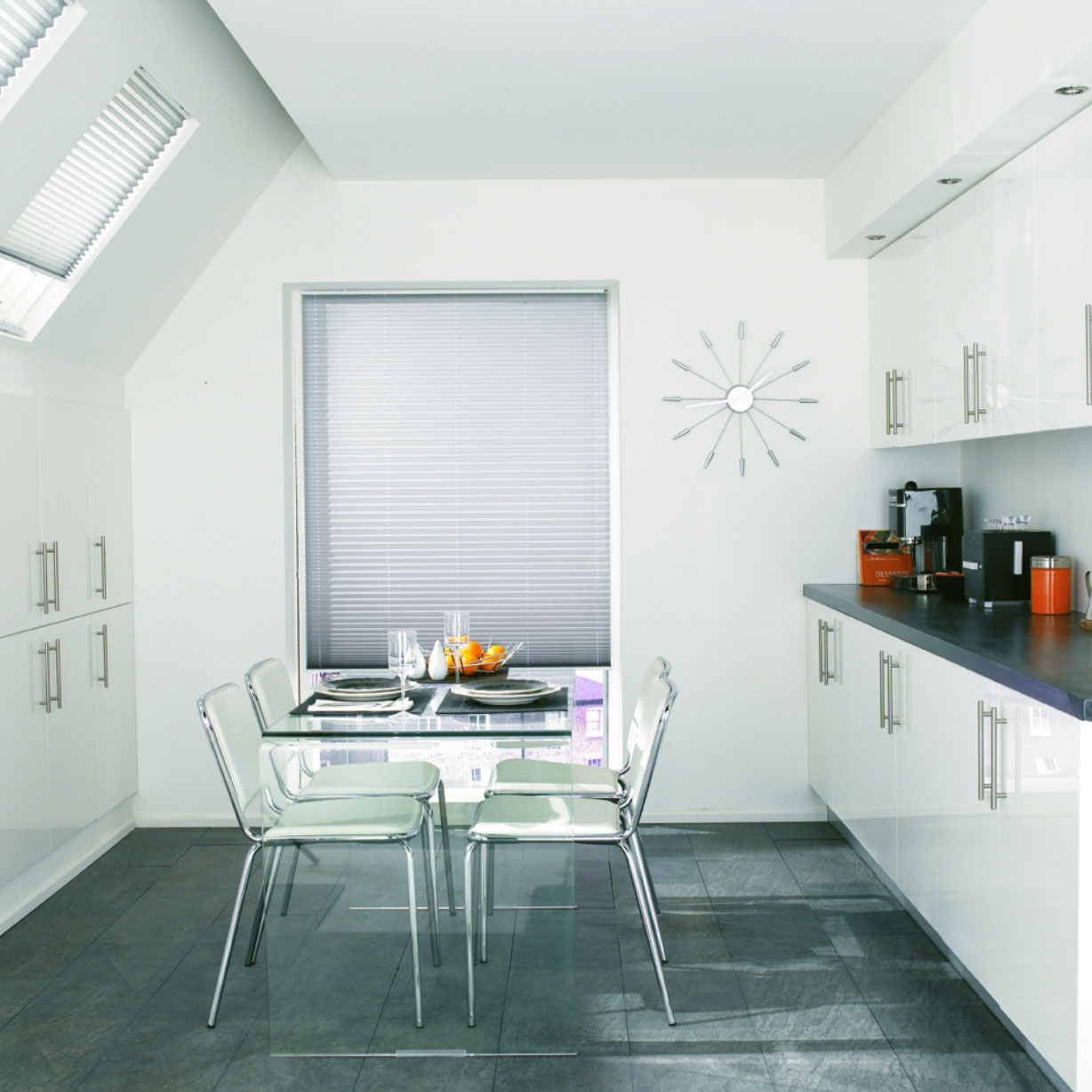 Grey and white pleated blinds in cool white modern kitchen with glass dining table and chairs