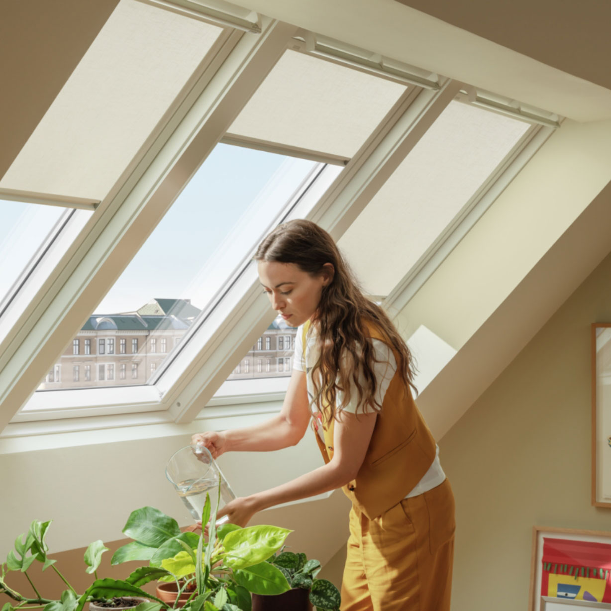 Woman watering houseplants under neutral Velux blinds